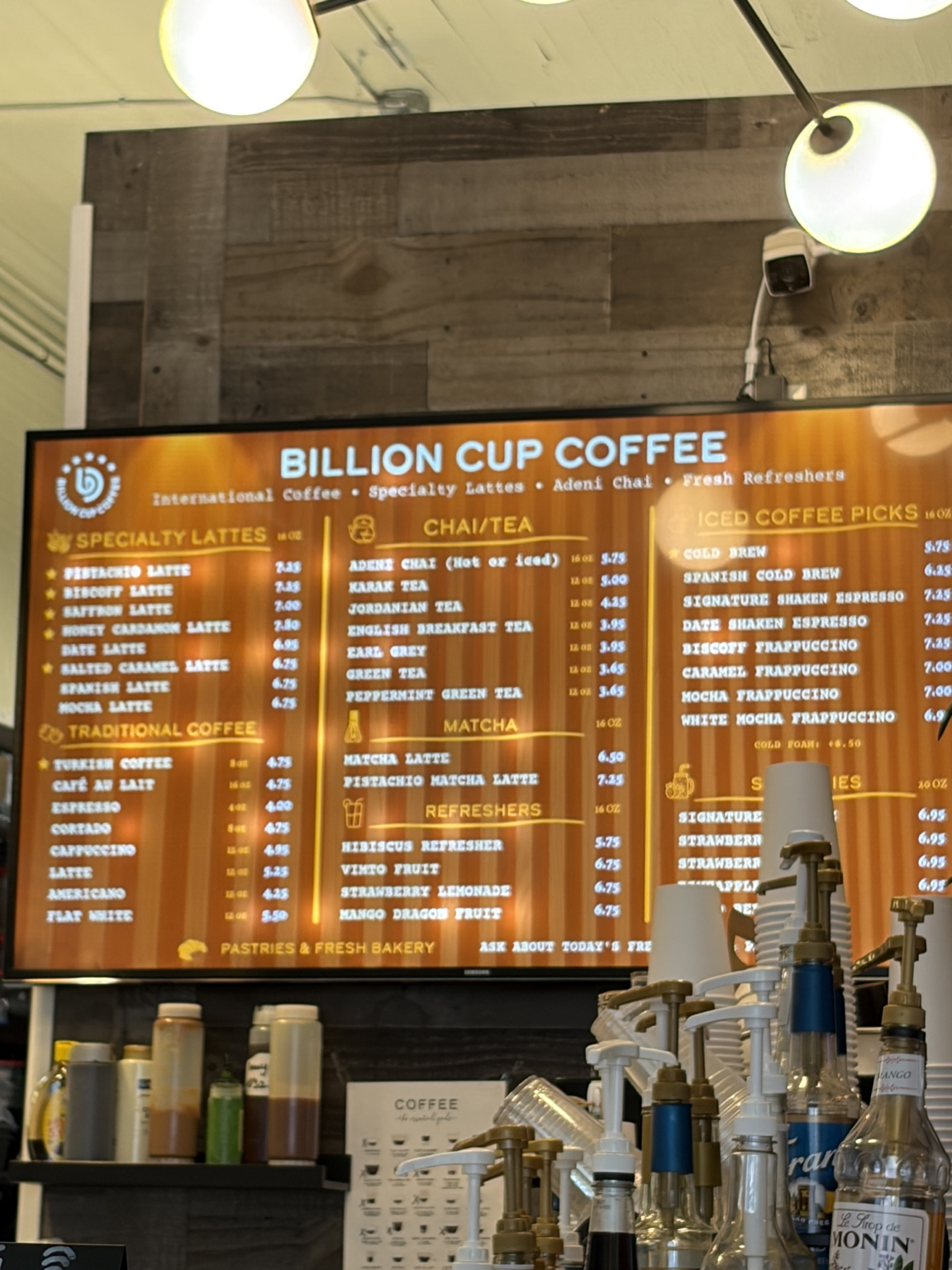 Billion Cup Coffee in-store menu board showing drink categories and prices; part of the smoothie section is blocked.